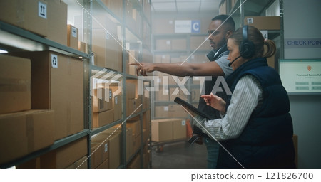African American Employee Scans Parcels, Female Warehouse Associate Uses Tablet Computer African American Employee Scans Parcels, Female Warehouse Associate Uses Tablet Computer 121826700