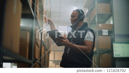 African American Inventory Manager Scans Cardboard Box, Uses Tablet Computer, Takes Package for Shipping African American Inventory Manager Scans Cardboard Box, Uses Tablet Computer, Takes Package for Shipping 121826702