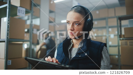 Female Customer Support Specialist in Logistics in Headset Talks on Call with Client, Uses Tablet Computer Female Customer Support Specialist in Logistics in Headset Talks on Call with Client, Uses Tablet Computer 121826709