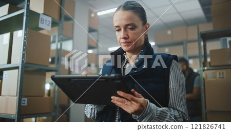 Female Logistics Specialist Uses Tablet Computer, Checks Inventory 121826741