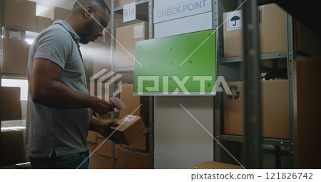 African American Warehouse Associate Checks Parcel Information at Terminal 121826742
