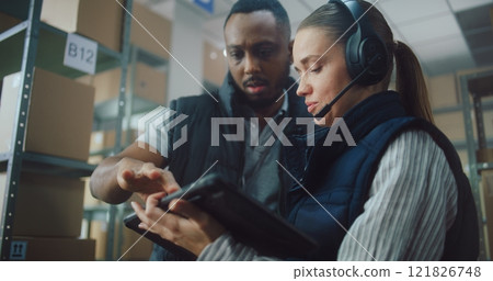 Multiethnic Warehouse Employees Having Discussion, Using Tablet Computer Multiethnic Warehouse Employees Having Discussion, Using Tablet Computer 121826748