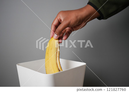 throwing banana in a garbage bin  121827760