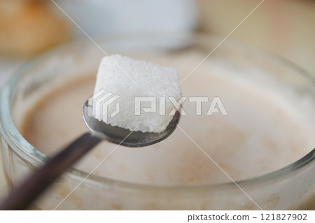A Sugar Cube Delicately Being Added to a Warm Cup of Coffee, Enhancing the Experience A Sugar Cube Delicately Being Added to a Warm Cup of Coffee, Enhancing the Experience 121827902