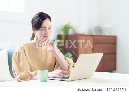 一位女士一臉困惑地使用電腦 121829354