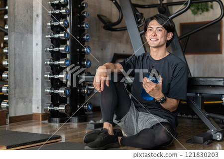 年輕的亞洲男子在健身房的休息和間歇期間喝水和蛋白質（補水） 121830203