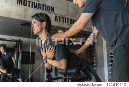 Young Asian man receiving personal training at a sports gym Young Asian man receiving personal training at a sports gym 121830245