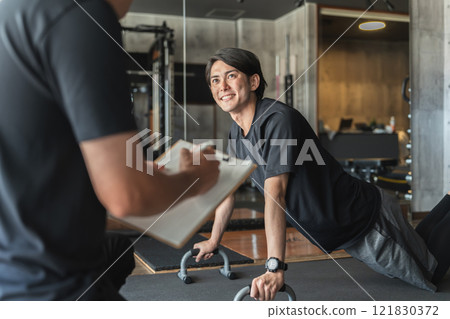 Young Asian man receiving personal training at a sports gym 121830372