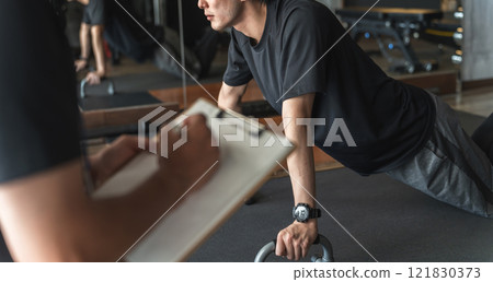年輕的亞洲男子在體育館接受個人訓練 年輕的亞洲男子在體育館接受個人訓練 121830373