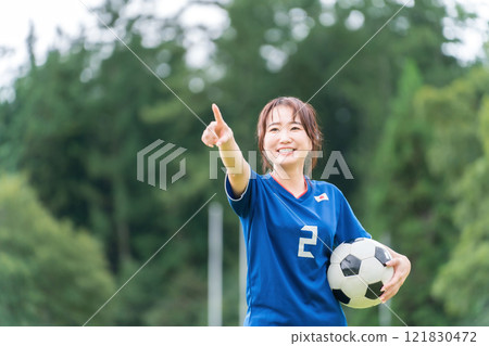 A Japanese woman who is a fan supporter playing soccer with a smile while holding a soccer ball 121830472