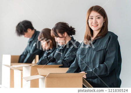 A woman working as a transportation, logistics, courier, distribution, delivery, or delivery company worker holding a cardboard box 121830524