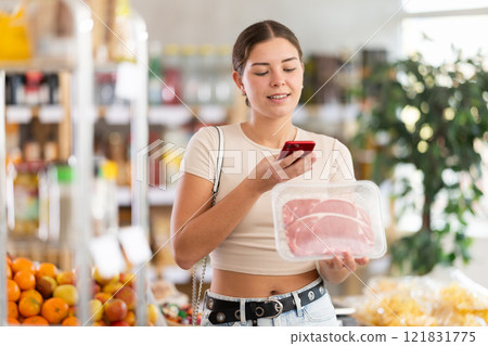 Girl scan QR-code on raw beef tenderloin package in store 121831775