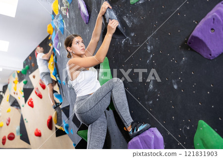 Young woman practicing rock climbing on climbing wall Young woman practicing rock climbing on climbing wall 121831903