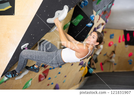 Motivated girl climbing without ropes on artificial bouldering wall Motivated girl climbing without ropes on artificial bouldering wall 121831907