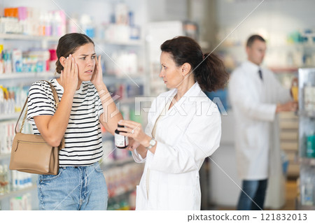 Female pharmacist advising headache medicine to woman Female pharmacist advising headache medicine to woman 121832013