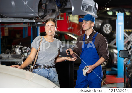 Young male mechanic giving car keys to woman client Young male mechanic giving car keys to woman client 121832014