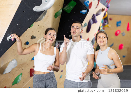 Group of friends planning climbing strategy at indoor bouldering gym Group of friends planning climbing strategy at indoor bouldering gym 121832019