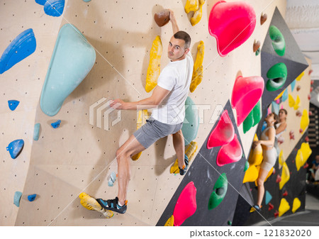 Young man practicing rock climbing on climbing wall Young man practicing rock climbing on climbing wall 121832020
