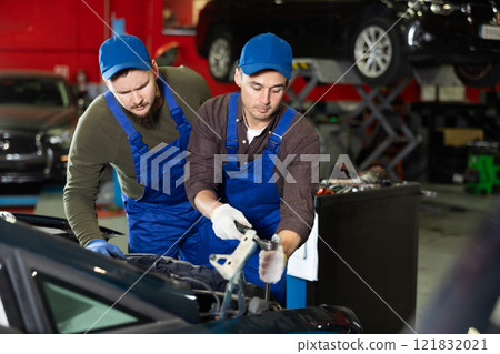 Two mechanic guys repairing car in car service 121832021
