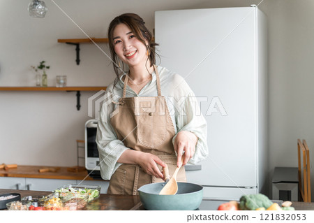 一位年輕的亞洲女性(母親、妻子、家庭主婦)在廚房裡做午餐盒 一位年輕的亞洲女性(母親、妻子、家庭主婦)在廚房裡做午餐盒 121832053