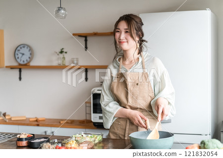一位年輕的亞洲女性(母親、妻子、家庭主婦)在廚房裡做午餐盒 一位年輕的亞洲女性(母親、妻子、家庭主婦)在廚房裡做午餐盒 121832054