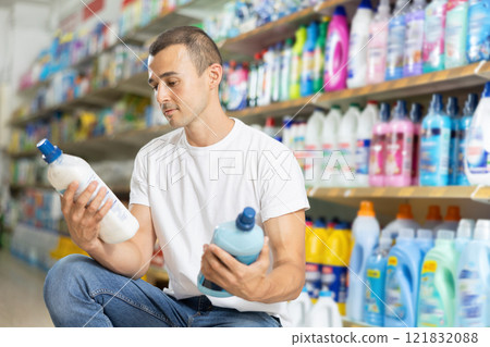Man carefully selects cleaning product in industrial section of supermarket 121832088