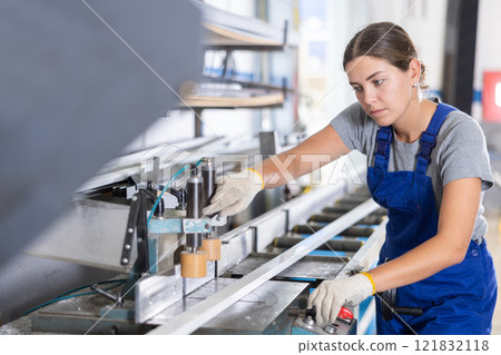 Workwoman cutting PVC profile on industrial machine in workshop Workwoman cutting PVC profile on industrial machine in workshop 121832118