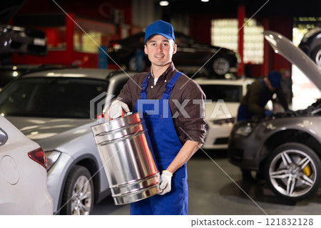 Positive male worker of car workshop holding metal fuel canister 121832128