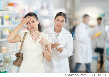 Female pharmacist advises medicine for head pain to woman 121832151