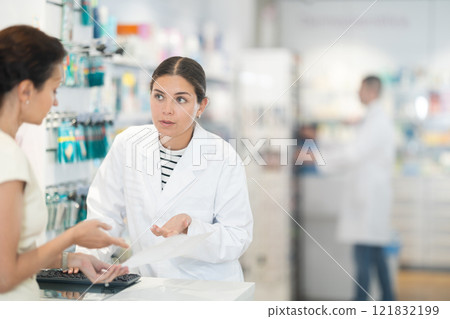 Young female pharmacist consulting woman client about medicine indicated in her recipe Young female pharmacist consulting woman client about medicine indicated in her recipe 121832199