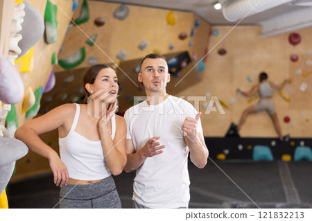 Young man and woman talking near climbing wall 121832213