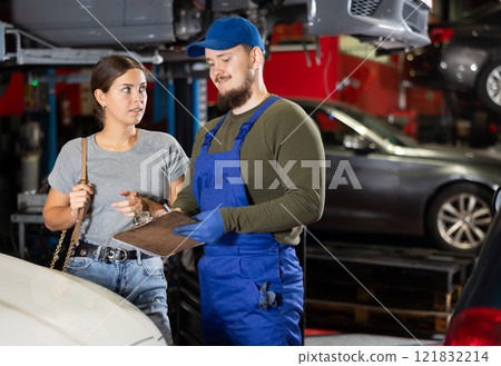 Mechanic guy signs agreement with young woman client 121832214