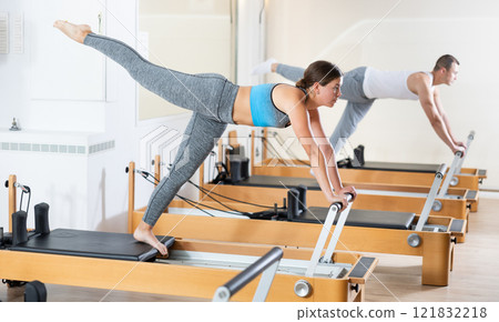 Athletic woman working out with straps in pilates studio Athletic woman working out with straps in pilates studio 121832218