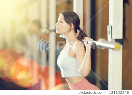 Young woman lifting barbell in gym 121832246