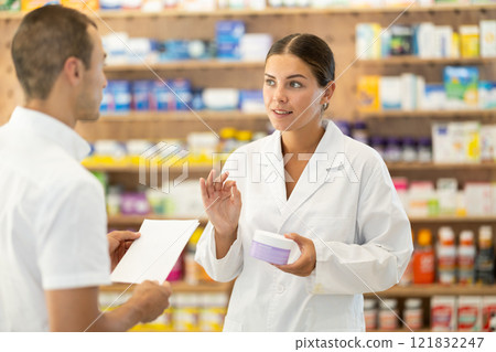 Female pharmacist consulting young guy about cosmetic cream 121832247