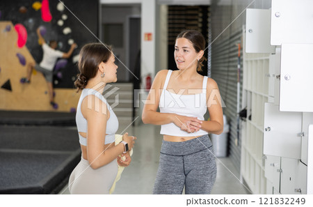 Smiling girl talking with female friend by lockers in bouldering gym 121832249