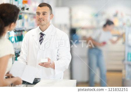 Male pharmacist speaking to woman customer buying medical preparation in drugstore Male pharmacist speaking to woman customer buying medical preparation in drugstore 121832251