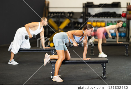 Young woman training with dumbbells on bench Young woman training with dumbbells on bench 121832380