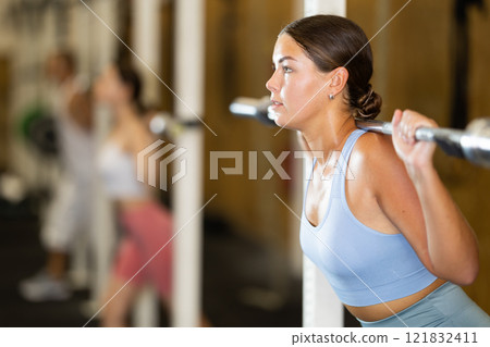 Young woman lifting barbell in gym 121832411