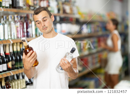 Male shopper selects wodka in produce section of supermarket 121832457