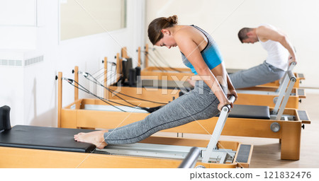 Girl doing stretching exercises on reformer in pilates studio 121832476