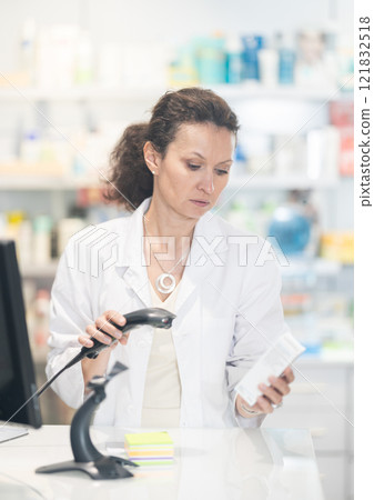 Middle-aged female pharmacist scanning barcode on medicine box Middle-aged female pharmacist scanning barcode on medicine box 121832518