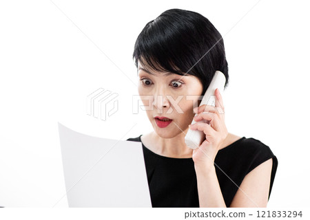 A middle-aged woman making a phone call with a surprised expression A middle-aged woman making a phone call with a surprised expression 121833294