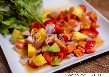 Spicy Salmon sashimi with mango salad served on plate 121833316