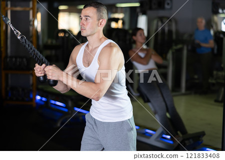 Man in sportswear training on rope loop simulator 121833408