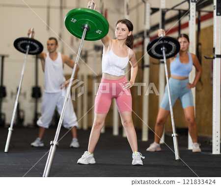 Young woman training with barbell in gym Young woman training with barbell in gym 121833424