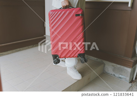Traveler lifting suitcase over step 121833641