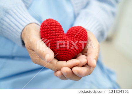 Asian elder senior woman patient holding red heart in hospital. Asian elder senior woman patient holding red heart in hospital. 121834501
