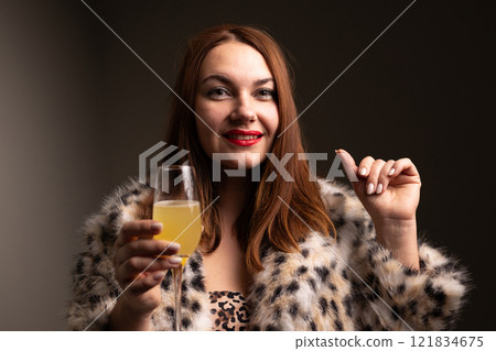 Chic and fashionable woman joyfully celebrating with a stylish drink in trendy attire 121834675