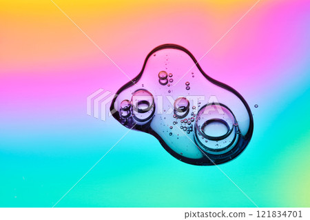 A drop of cosmetic serum on a multicolored background in shades of blue and lilac. A drop of cosmetic serum on a multicolored background in shades of blue and lilac. 121834701